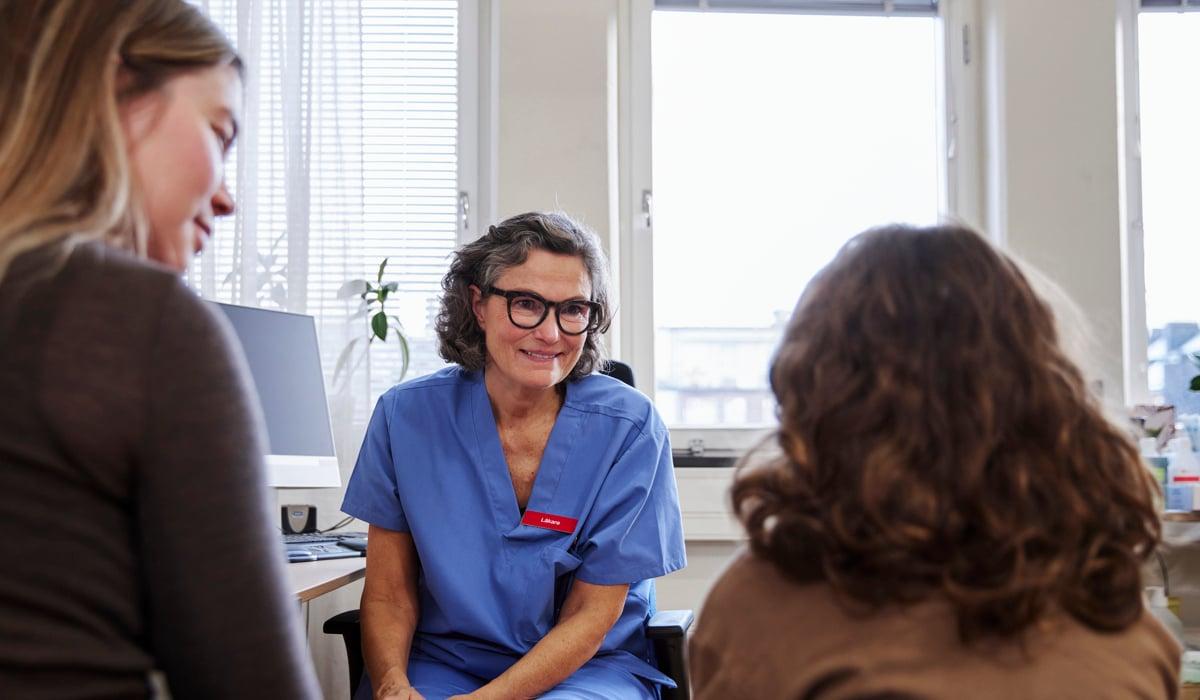 Kvinnlig läkare i samtal med två patienter